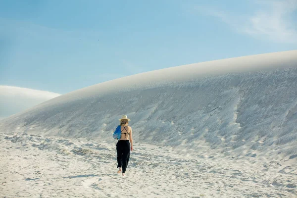 Woman walking on white  sand dune in desert in summer