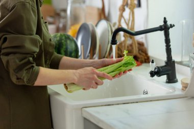 Mutfakta kereviz yıkayan kadın.