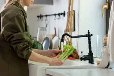 Mutfakta kereviz yıkayan kadın.