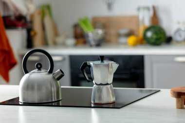 Mutfaktaki masada gümüş moka demliği var. 