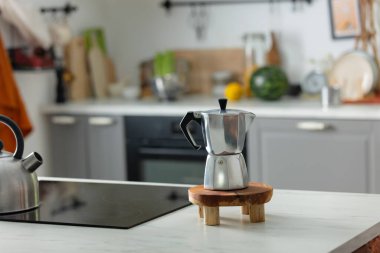 Mutfaktaki masada gümüş moka demliği var. 