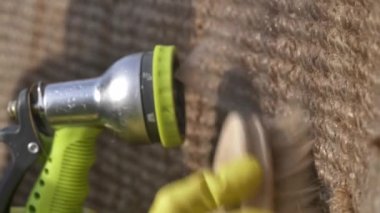 Kadın dışarıda çevre dostu bir halı yıkıyor ve ıslatıyor.