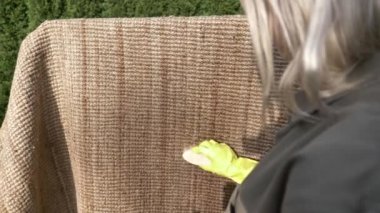 Kadın dışarıda çevre dostu bir halı yıkıyor ve ıslatıyor.