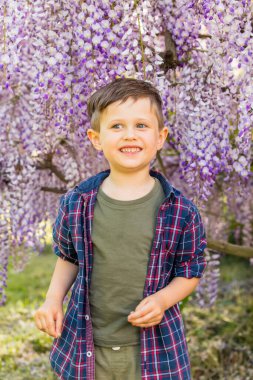 Bahçedeki çiçek açan ağacın yanında küçük bir çocuk 