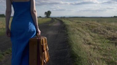 Polonya 'da kırsal yolda bavullu bir kadın yürüyor.