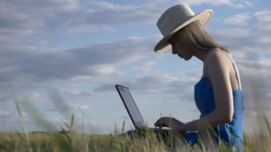 Dizüstü bilgisayarı olan kadın kırsal yolda oturuyor.