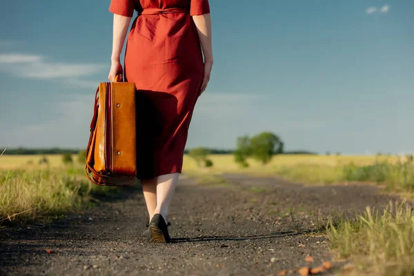 Девушка Красном Платье Чемоданом Проселочной Дороге Закате Низкий Вид — стоковое фото