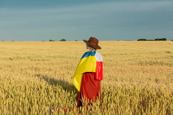 ウクライナとポーランドの旗を背景に小麦のフィールドと青空で女の子 — ストック写真