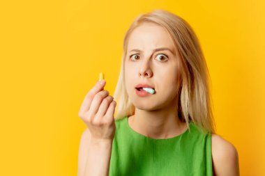 Sarı arka planda hapları olan yeşil elbiseli şık bir kız.