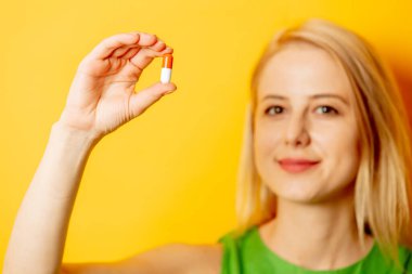 Sarı arka planda haplı yeşil elbiseli şık bir kız.