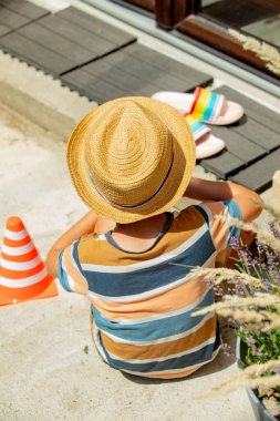 Arkaya bakan bir çocuk kumdaki bahçede oynuyor.