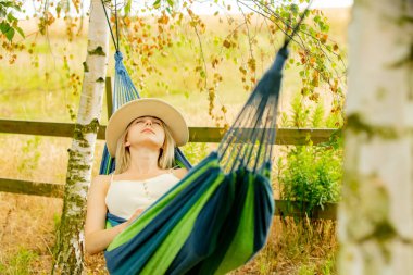 Tired mother tries to sleep in hammock in garden