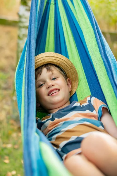 Happy kid boy in hammock in summer garden