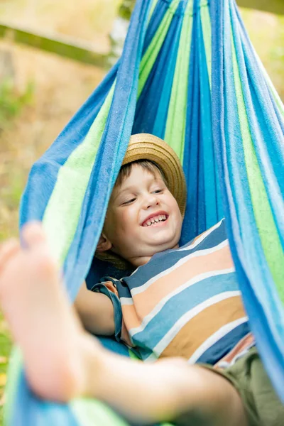 Happy kid boy in hammock in summer garden