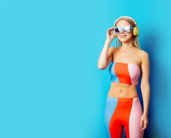 Stylish Blond Woman Colored Swimming Suit Headphones Sunglasses Blue Background — ストック写真