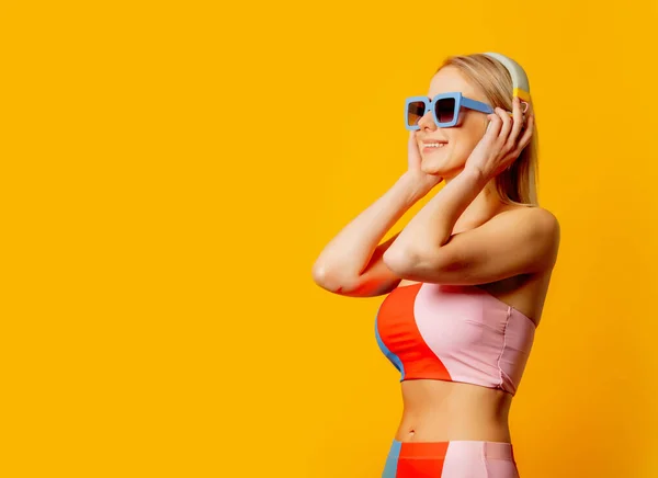 Stylish Blond Woman Colored Swimming Suit Headphones Sunglasses Yellow Background — Stockfoto
