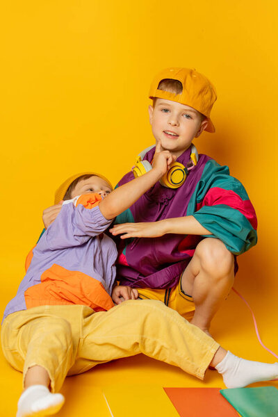 Two kids in stylish vintage 80s clothes have a fun on yellow background