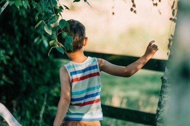 Back side view on little boy in village