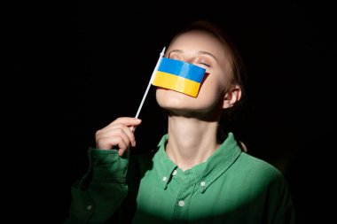 Stylish woman in shirt hold ukrainian flag with light focus 