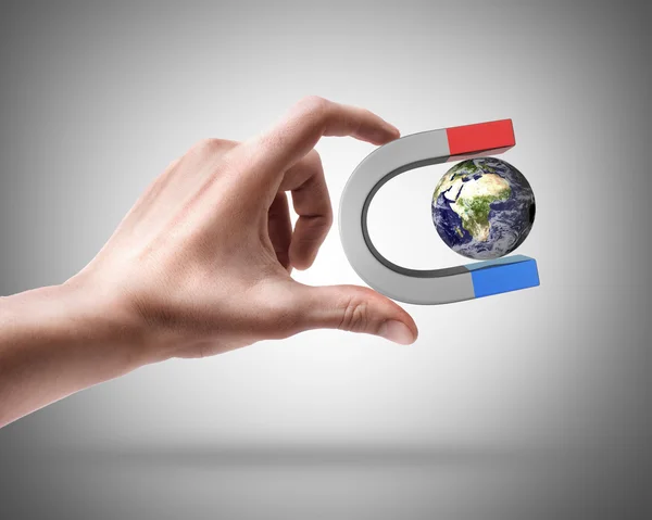 Man's hand holding Magnet and Earth — Stock Photo, Image