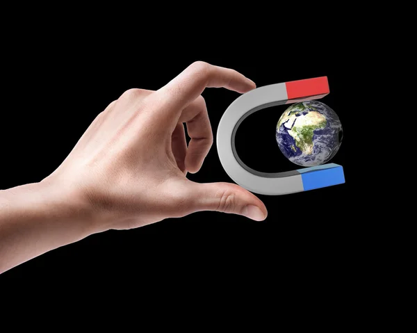 Man 's hand holding Magnet and Earth — стоковое фото
