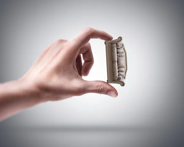 Mão de homem segurando mini sofá — Fotografia de Stock