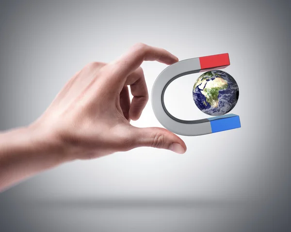 Hand holding Magnet and Earth — Stock Photo, Image