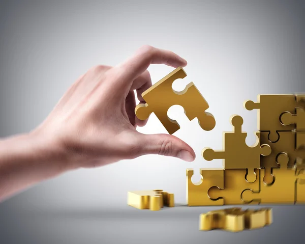 Hand holding golden puzzle — Stock Photo, Image