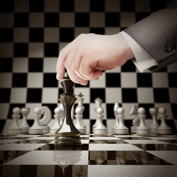 Mano sosteniendo figura blanca de ajedrez en tablero de ajedrez —  Fotos de Stock