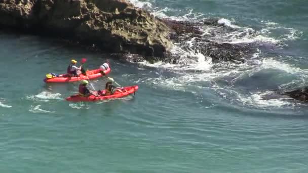 Red canoes near rocks in the sea — Stock Video