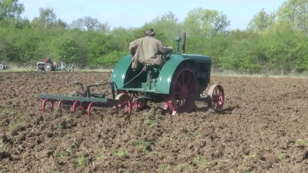 Green vintage tractor pulling a harrow — Stock Video