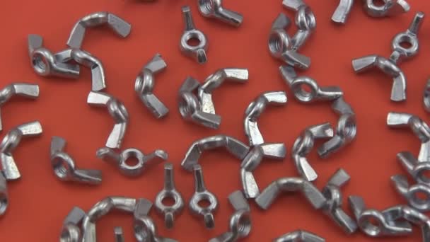 Chrome wing nuts rotating on a red  background. — Stock Video