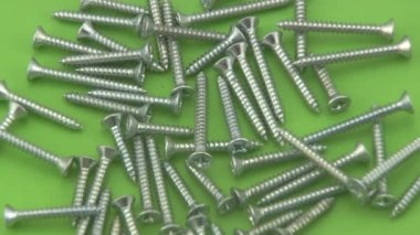 yeşil bir arka plan üzerinde dönen krom crosshead vidaları.