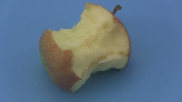 Teil gegessen Apfel auf einem rotierenden blauen Hintergrund. — Stockvideo