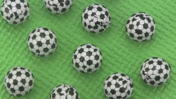 Yeşil bir arka plan üzerinde dönen şeker futbol topları. — Stok video