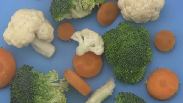 Légumes mélangés sur fond bleu . — Video