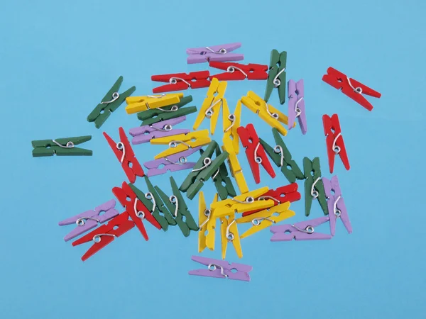 Close up of multicoloured clothes peg shaped paper clips on a blue background — Stock Photo, Image