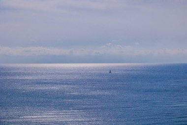 Su, gökyüzü ve yelkenli tekneleri olan güzel, sakin bir deniz manzarası.