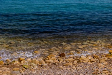 Mavi denizin ve bej taşlı kıyıların güzel, sakin arka planı