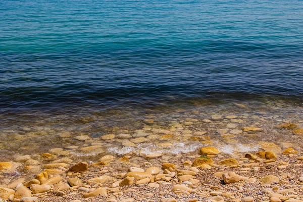 Mavi denizin ve bej taşlı kıyıların güzel, sakin arka planı