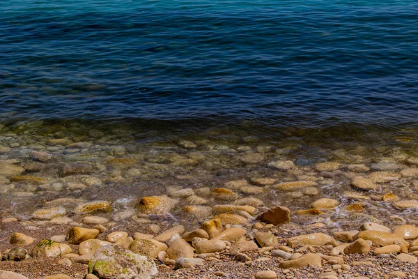 Mavi denizin ve bej taşlı kıyıların güzel, sakin arka planı