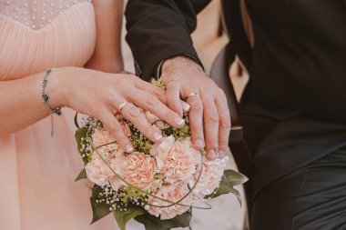  Düğünden hemen sonra nikah yüzüklü gelin ve damadın elleriyle bej bir düğün buketi.