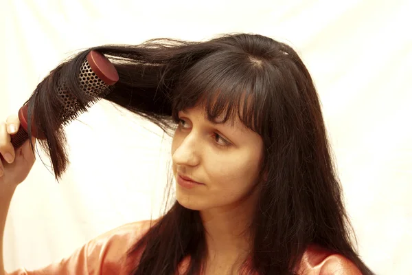 The woman combs hair the hair dryer — Stock Photo, Image