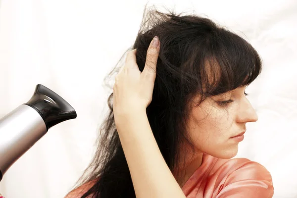 Kobieta wysusza włosy suszarką do włosów — Zdjęcie stockowe
