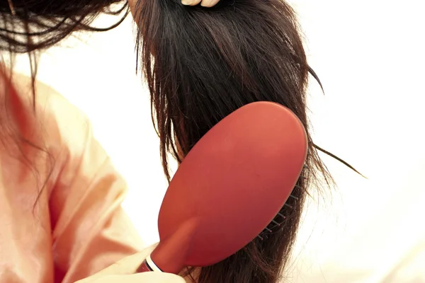 Kobieta grzebienie do włosów suszarką do włosów — Zdjęcie stockowe