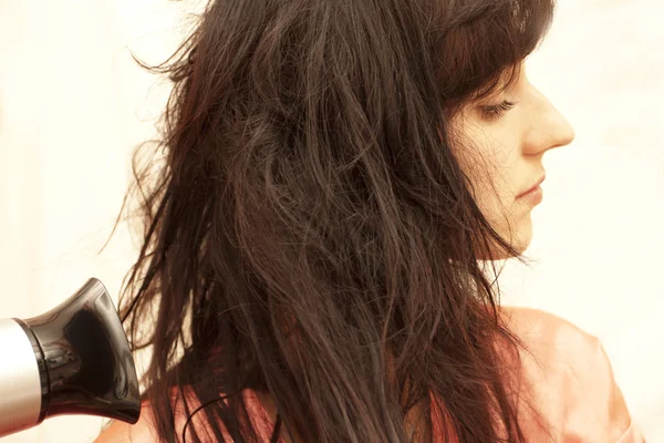 Kobieta wysusza włosy suszarką do włosów — Zdjęcie stockowe