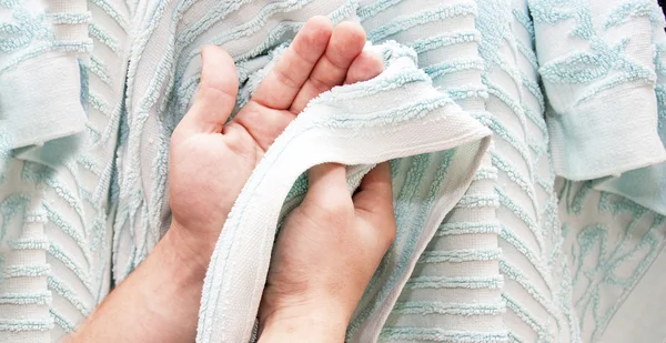 Torka av händerna en blå frottéhandduk — Stockfoto