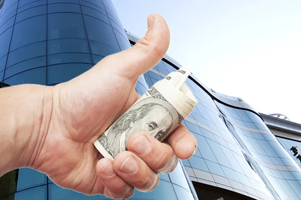 Hand with notes of dollars against office building — Stock Photo, Image