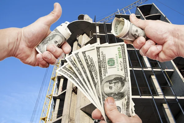 Händer med anteckningar dollar mot huset under konstruktion — Stockfoto