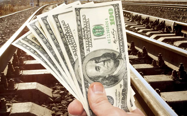 Руки с долларовыми купюрами против железной дороги — стоковое фото